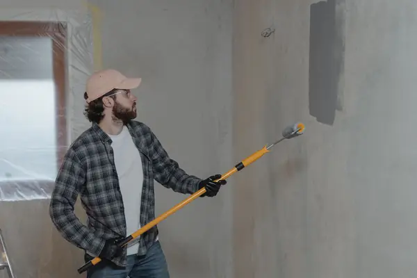 Painter rolling grey paint onto an interior wall in Stockton